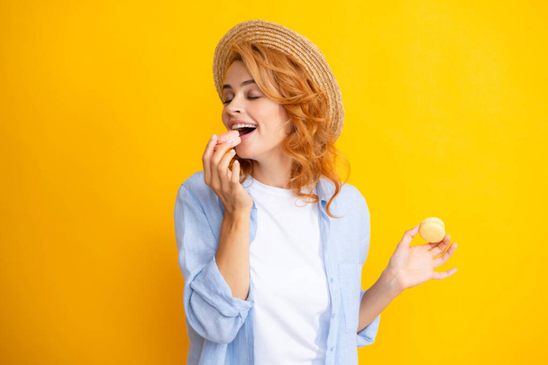 Чарівна жінка хоче вкусити смачного макарона, тримаючи макаруни біля відкритого рота, дівчина краси насолоджується цукерками
. - Фото, зображення
