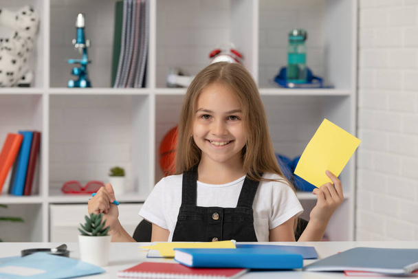 happy child holding paper and scissors in school classroom - Foto, imagen