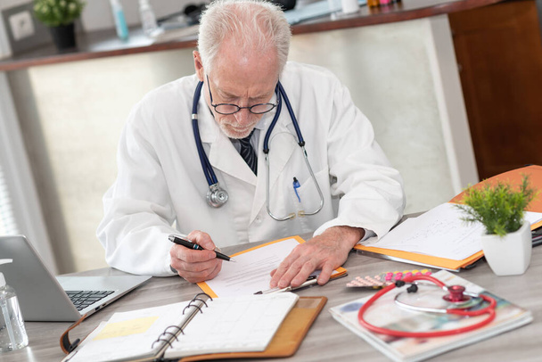 Médecin principal lisant un dossier clinique au cabinet médical - Photo, image