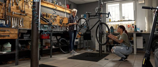 Female workers fix or install wheels on bicycle - Zdjęcie, obraz