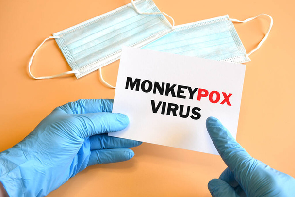 Doctor hand in blue glove indicate Monkeypox Virus words on white paper. Monkeypox on white paper. Medical and Monkeypox virus pandemic concept. - Photo, Image