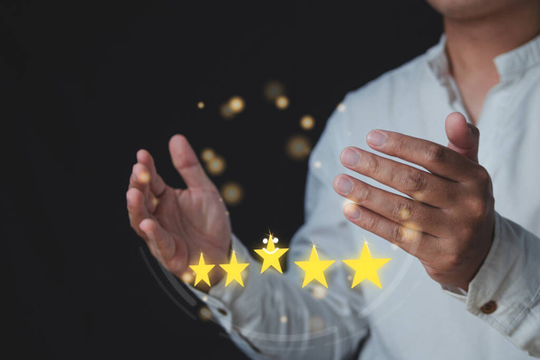 Customer review concept. Among hands, there are five stars for Excellent job. Close up shot with some noise and film gain. The man wears white shirt and gold light bokeh.  - Photo, Image