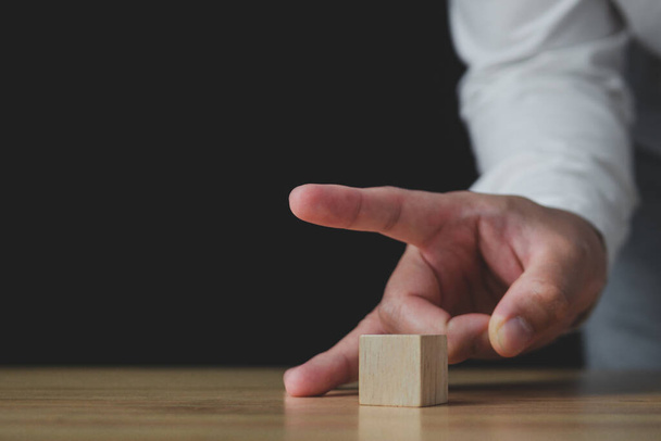 Someone uses fingers to flick a wood block. In the business, it shows a selling or cutting of some business to stop loss. Strategy Idea. This close up shot with some slightly focus.  - Photo, Image