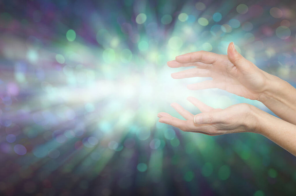 Healer canalização de alta ressonância Cura Energia - fêmea copa mãos com luz entre contra um fundo efeito bokeh verde e espaço para mensagens - Foto, Imagem