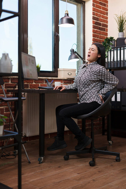 Firma finansowa wyczerpana bizneswoman z poważnym bólem pleców siedzi na krześle w miejscu pracy - Zdjęcie, obraz