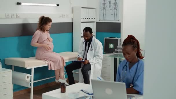 Reunião médica masculina com paciente esperando criança no gabinete - Filmagem, Vídeo