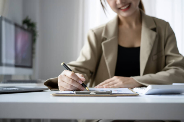 Cortada tiro sorrindo gerente de finanças do sexo feminino planejamento de projetos de trabalho na mesa de escritório. - Foto, Imagem