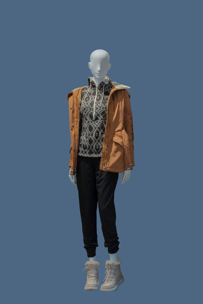 Full length image of a female display mannequin wearing warm fashionable clothes isolated on blue background - Photo, Image
