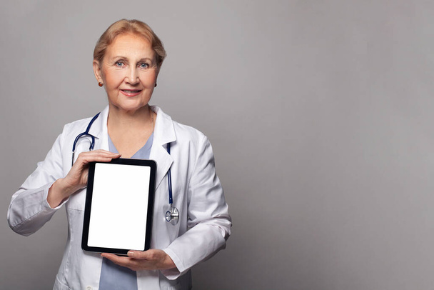 Feliz médico con PC tableta con pantalla táctil blanca vacía sobre fondo azul - Foto, imagen