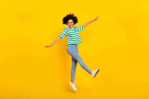Full body photo of funky millennial lady jump wear t-shirt jeans footwear isolated on yellow color background - Foto, afbeelding
