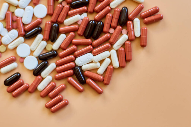 Flat leggen verschillende kleurrijke medische pillen op oranje achtergrond, vitamine deficiëntie, avitaminosis concept, diverse farmaceutische pillen, voedingssupplement gezondheidszorg product. - Foto, afbeelding