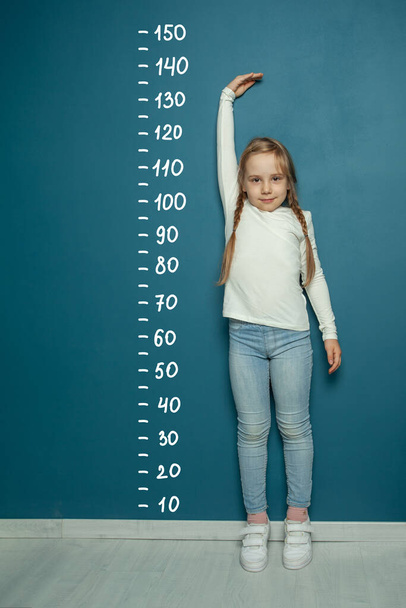 Bambino misura l'altezza su sfondo blu - Foto, immagini