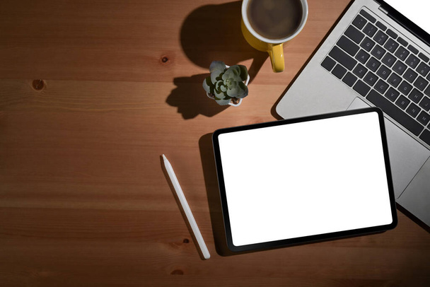 Tablet digitale con schermo bianco, laptop e tazza di caffè su sfondo di legno. Posa piatta. - Foto, immagini