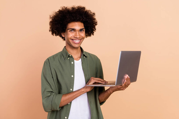 Portrait of attractive cheerful skilled wavy-haired guy agent broker using laptop developing isolated over beige pastel color background - Fotoğraf, Görsel