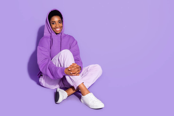 Full body photo of cute millennial lady sit wear hoodie trousers shoes isolated on purple color background - Photo, Image