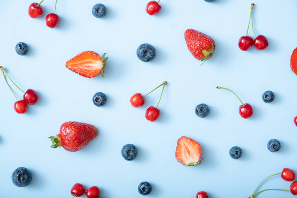 Muster mit Erdbeeren, Kirschen und Himbeeren auf blauem Hintergrund. - Foto, Bild