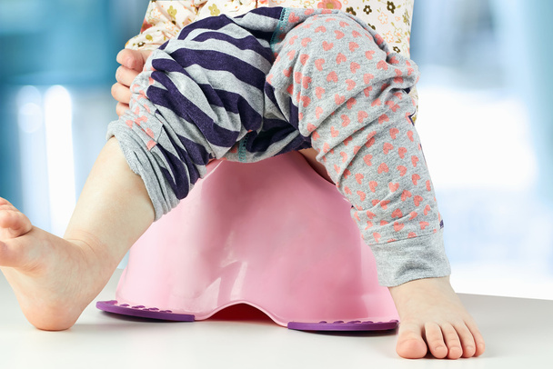 Children's benen opknoping neer uit een kamer-pot - Foto, afbeelding
