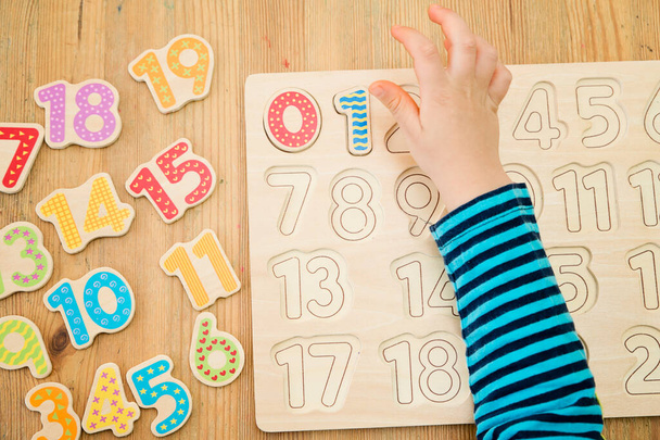 Kid learning numbers through game. Activity with wooden numbers. Educations at home, pre-school education, Montessori methodology. Toy to learn counting and stimulate imagination, creativity - Photo, Image