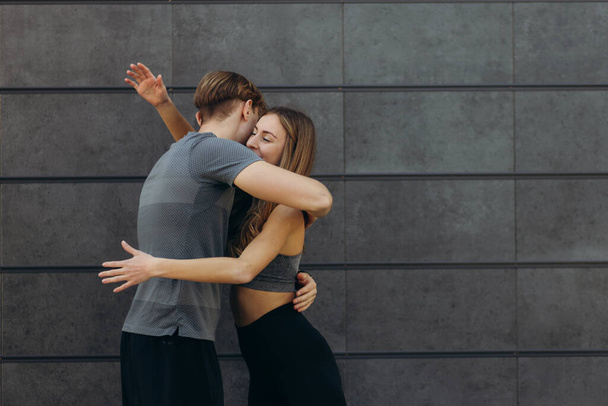 Fit beautiful woman and handsome muscular man after outdoor training, hugging and smiling. Couple. Healthy, sporty lifestyle concept. Real people emotions - 写真・画像