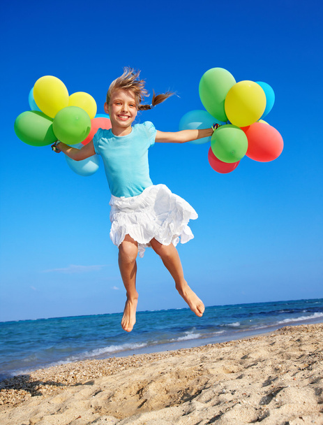 Дитина грає з повітряними кулями на пляжі
 - Фото, зображення