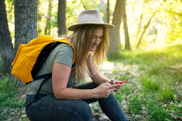 Женщина в шляпе с помощью смартфона на открытом воздухе. - Фото, изображение
