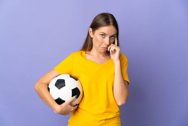 Молодая литовская футболистка изолирована на фиолетовом фоне, думая об идее - Фото, изображение