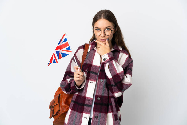 Joven lituana sosteniendo una bandera del Reino Unido aislada sobre fondo blanco pensando - Foto, Imagen