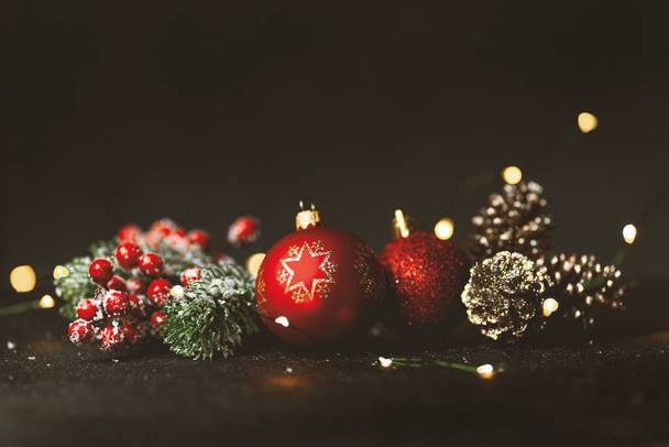 New Year and Christmas decoration, holiday background. Red festive ball bauble, green fir (xmas tree) and yellow blurred lights. Toned on vintage style. - Фото, изображение