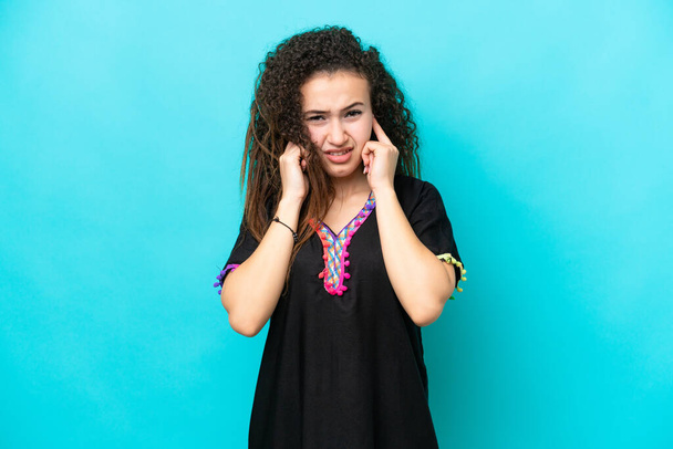Young Arab woman isolated on blue background frustrated and covering ears - Photo, Image