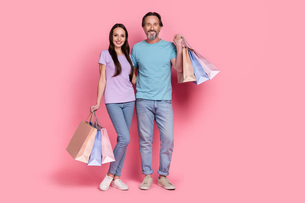 Full size photo of two cheerful nice partners embrace hold packages isolated on pink color background - Valokuva, kuva
