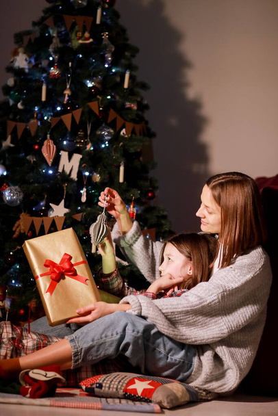 young mother and daughter open Christmas Lighting Present Gift Box front of Xmas Tree. Happy Mom with kid girl in Magic Night. Family merry christmas and new year holiday concept. High quality photo. - Zdjęcie, obraz