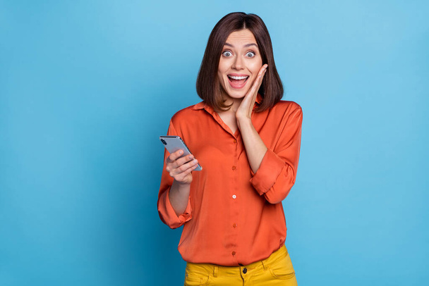 Portrait of attractive cheerful amazed girl using device blogging having fun isolated over bright blue color background - Foto, immagini