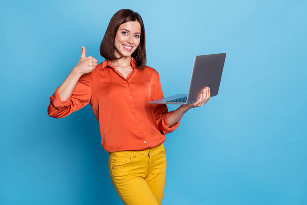 Photo of young lady hold laptop show thumb-up select advertise perfect approve isolated over blue color background - Foto, afbeelding