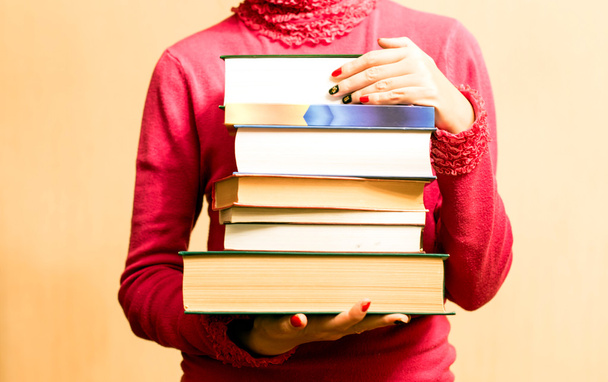 Femme en pull rouge avec des livres à la main
  - Photo, image