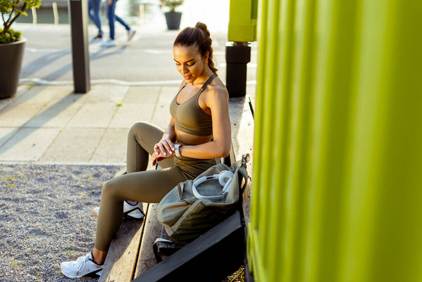 Pretty young woman takes a break after running in the urban area - 写真・画像