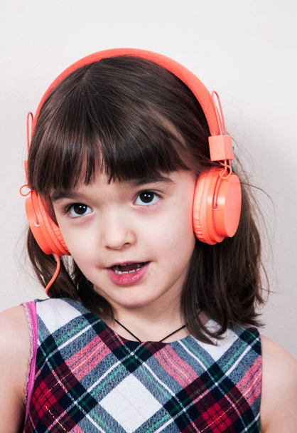 Pikkutyttö käyttää kuulokkeita - Valokuva, kuva