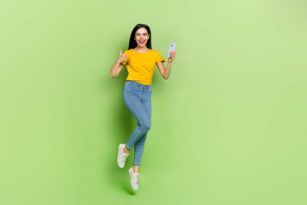 Full body portrait of overjoyed carefree person show thumb up hold gadget isolated on green color background. - Fotografie, Obrázek