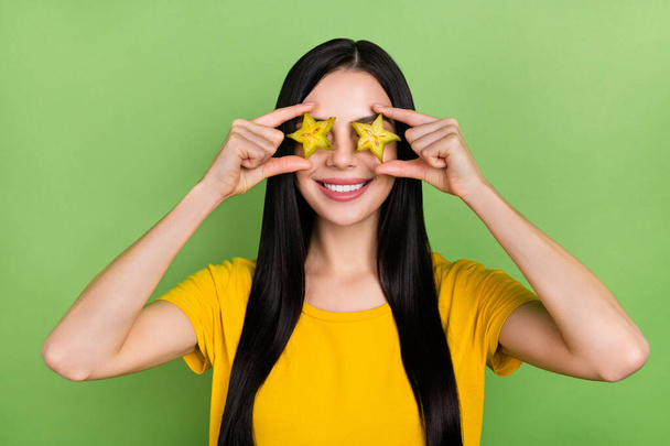 Photo of childish fooling woman wear yellow t-shirt holding tropical fruit cover eyes isolated green color background. - Foto, Imagen