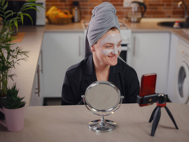 Beroemde blogger. Vrolijke vrouwelijke vlogger tonen schoonheid masker tijdens het opnemen van video en het geven van tips voor haar schoonheid blog. Vrouw test nieuw product. cosmetisch gezichtsmasker - Foto, afbeelding