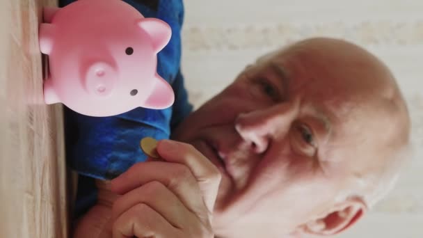 Ein älterer Mann aus dem Kaukasus wirft Münzen in ein Sparschwein. Hochwertiges 4k Filmmaterial - Filmmaterial, Video