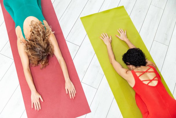 Two yoga women practice yoga on a mat in yoga studio - Fotó, kép
