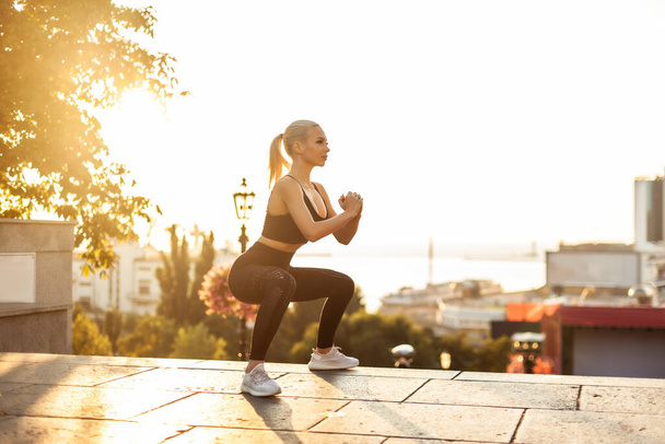 Mujer fitness entrena los músculos de las piernas en la ciudad por la mañana temprano - Foto, Imagen