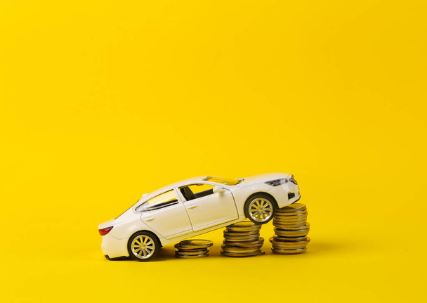 Model hraček s hromadou mincí na žlutém pozadí. Úspora peněz, investice, nákup automobilového konceptu - Fotografie, Obrázek