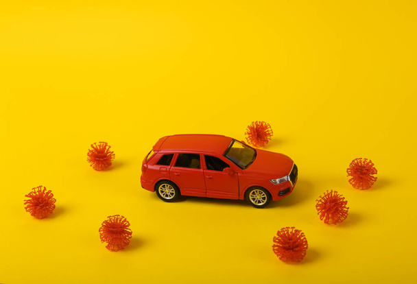Modelo de coche de juguete con una cepa de virus sobre un fondo amarillo. Proteja su concepto de salud - Foto, Imagen