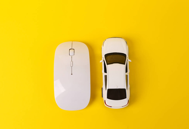 Speelgoedauto model met pc muis op gele achtergrond - Foto, afbeelding