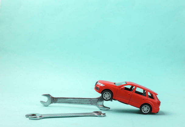 Modelo de coche de juguete con llave inglesa sobre fondo azul. Servicio automático, concepto de reparación. - Foto, imagen