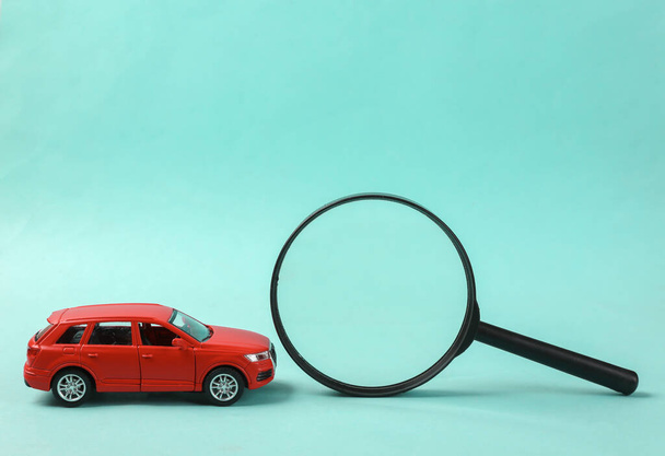 Toy car model and magnifying glass on blue background - Фото, зображення