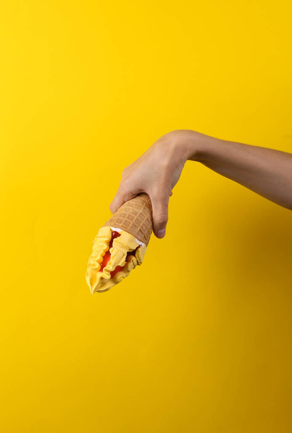 Female hand holds ce cream cone on a yellow background. Summer background - Valokuva, kuva