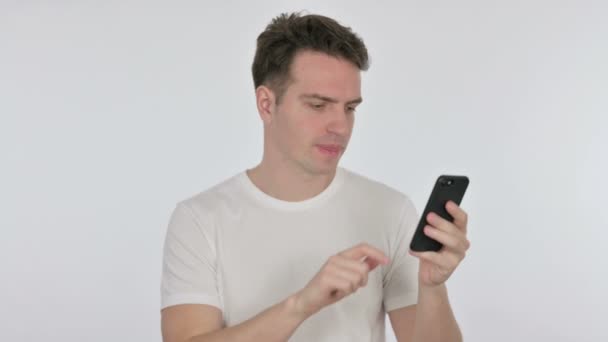 Casual νεαρός άνδρας απώλεια για Smartphone σε λευκό φόντο  - Πλάνα, βίντεο
