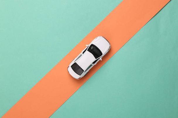 Giocattolo modello di auto cavalca su una striscia rosa su uno sfondo blu. Vista dall'alto - Foto, immagini